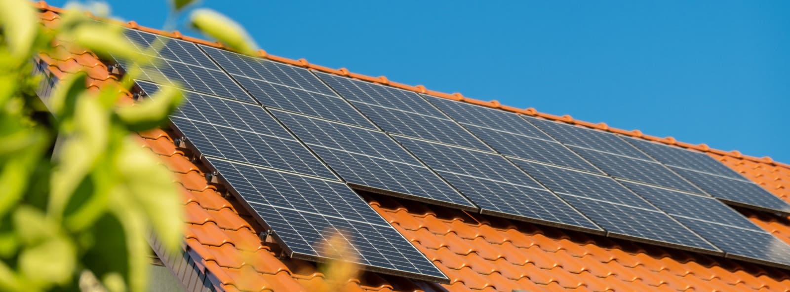 Painéis solares no telhado de uma casa sob céu azul, representando energia solar residencial.