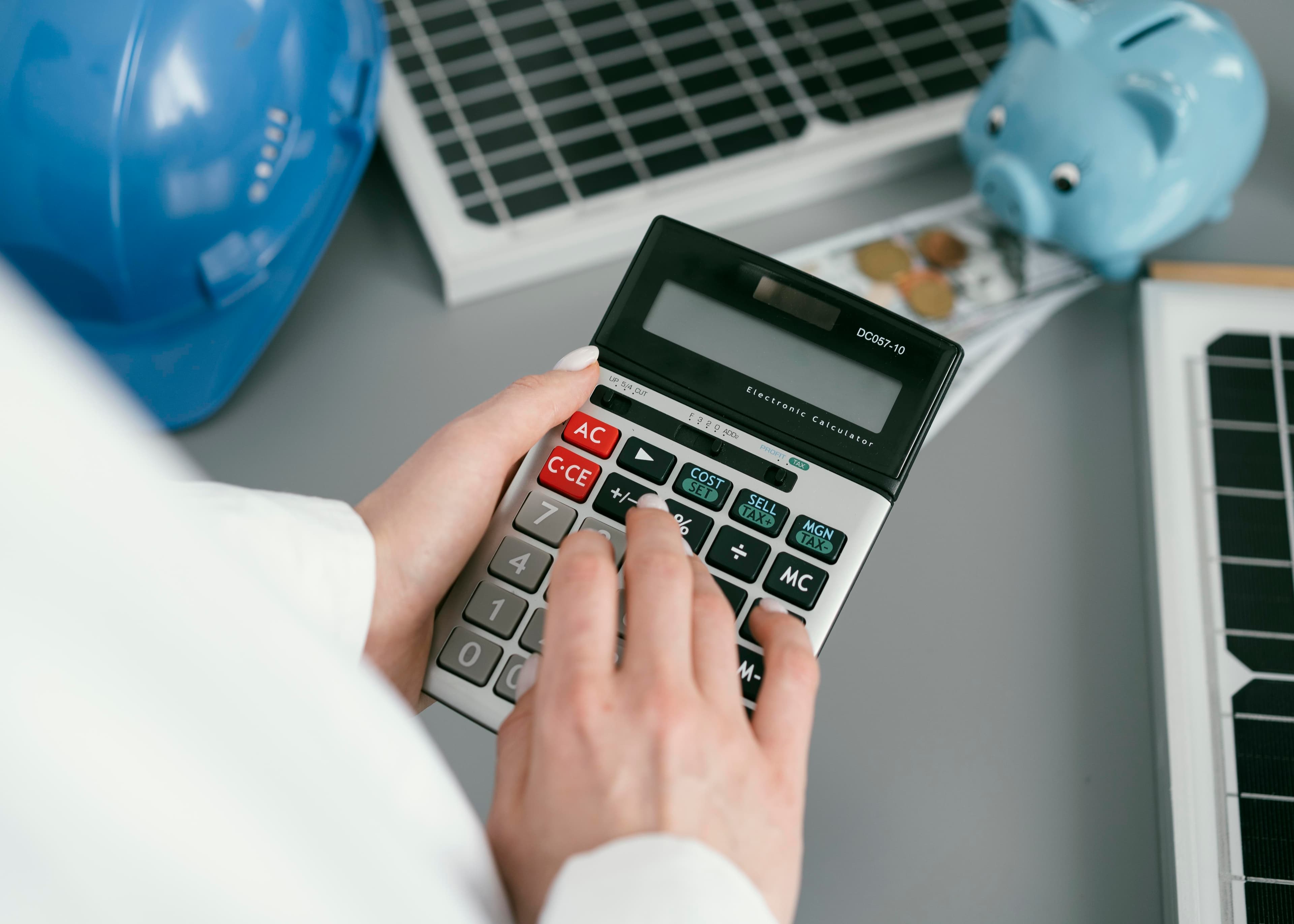 Mão segurando calculadora para fazer as contas do orçamento, ilustrando o aumento da conta de luz